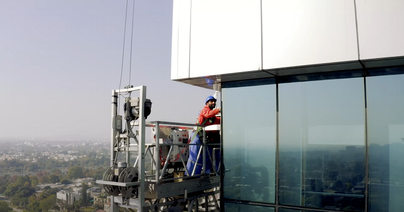 Suspended building maintenance platform operating along a high-rise glass façade