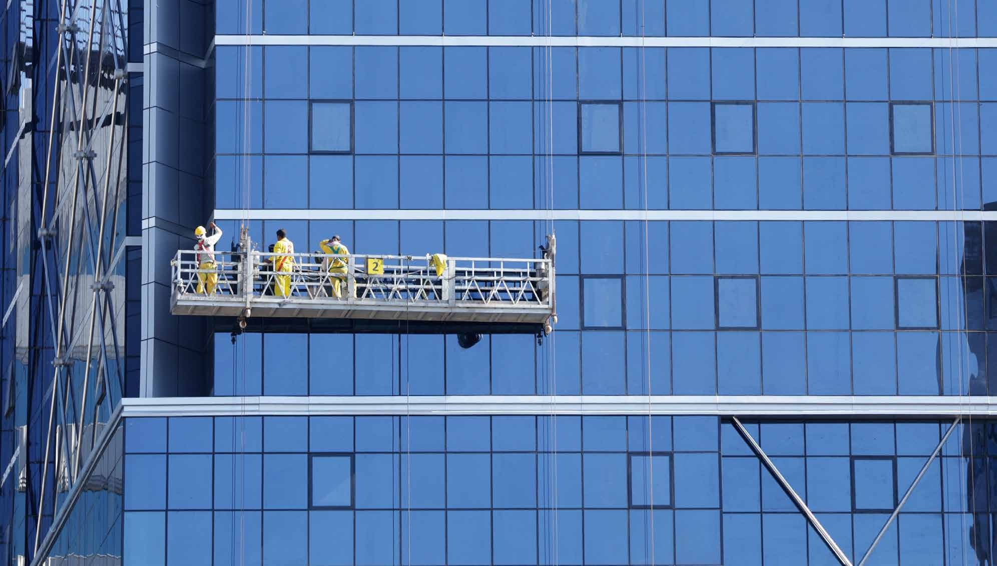 Suspended building-maintenance platform beside a glass façade, from the BRUGG conductor-rope brochure